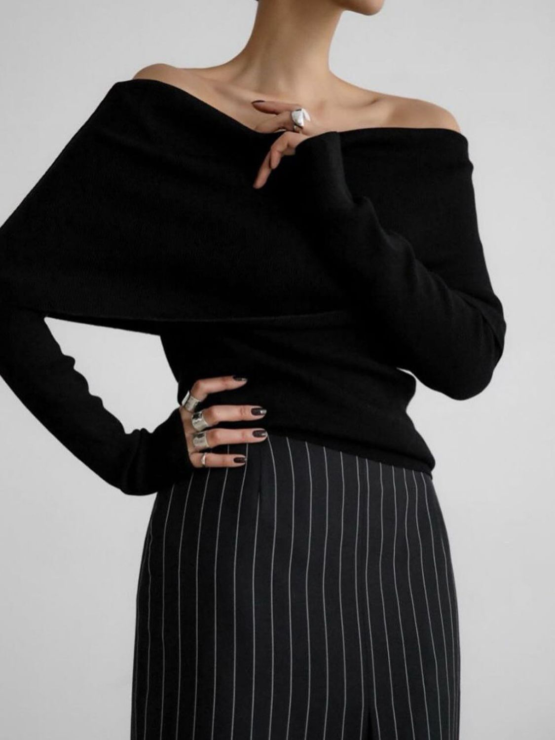 Woman wearing stylish black off-shoulder long sleeve knit top