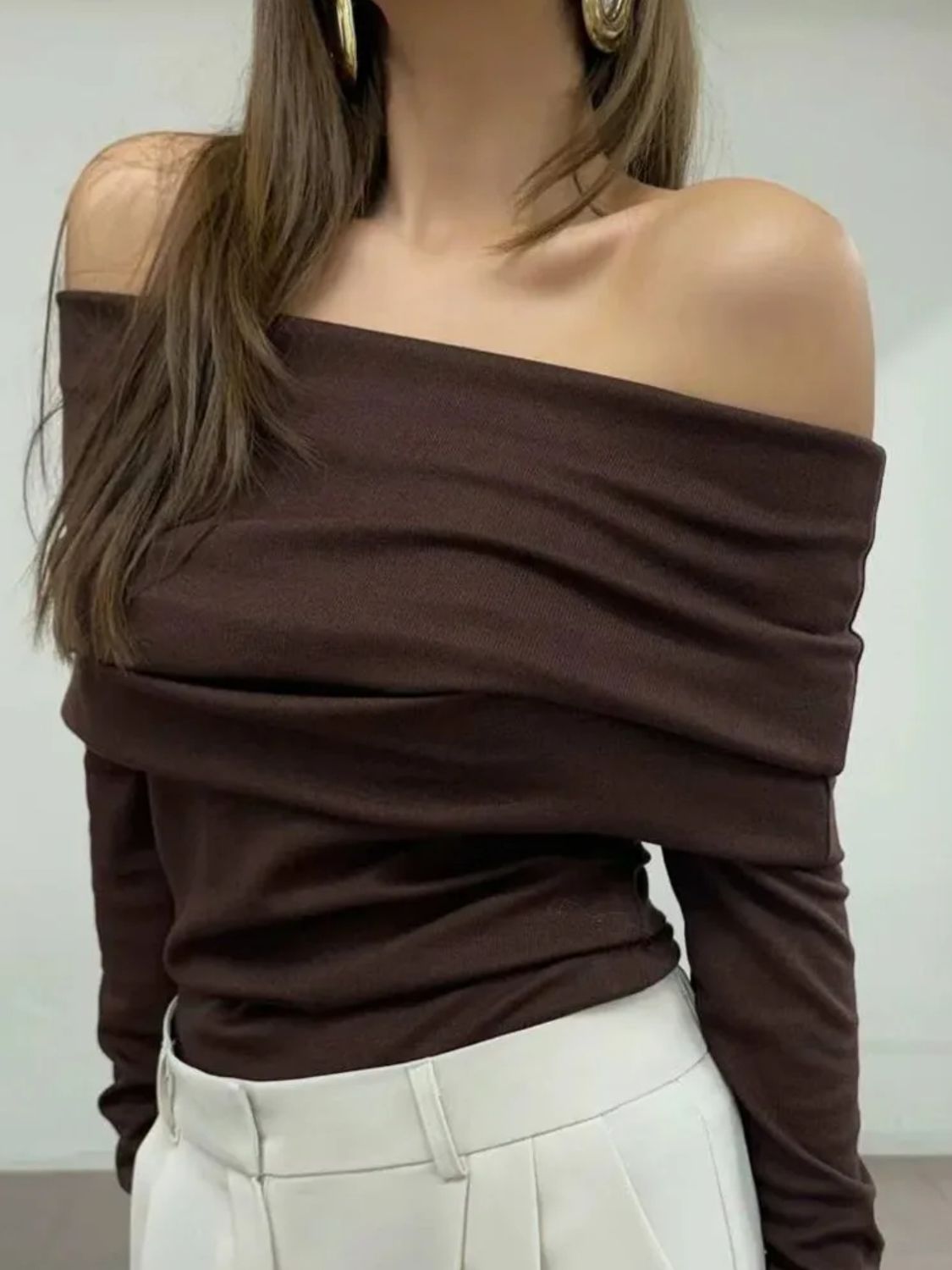 Woman wearing stylish brown off-shoulder long sleeve knit top