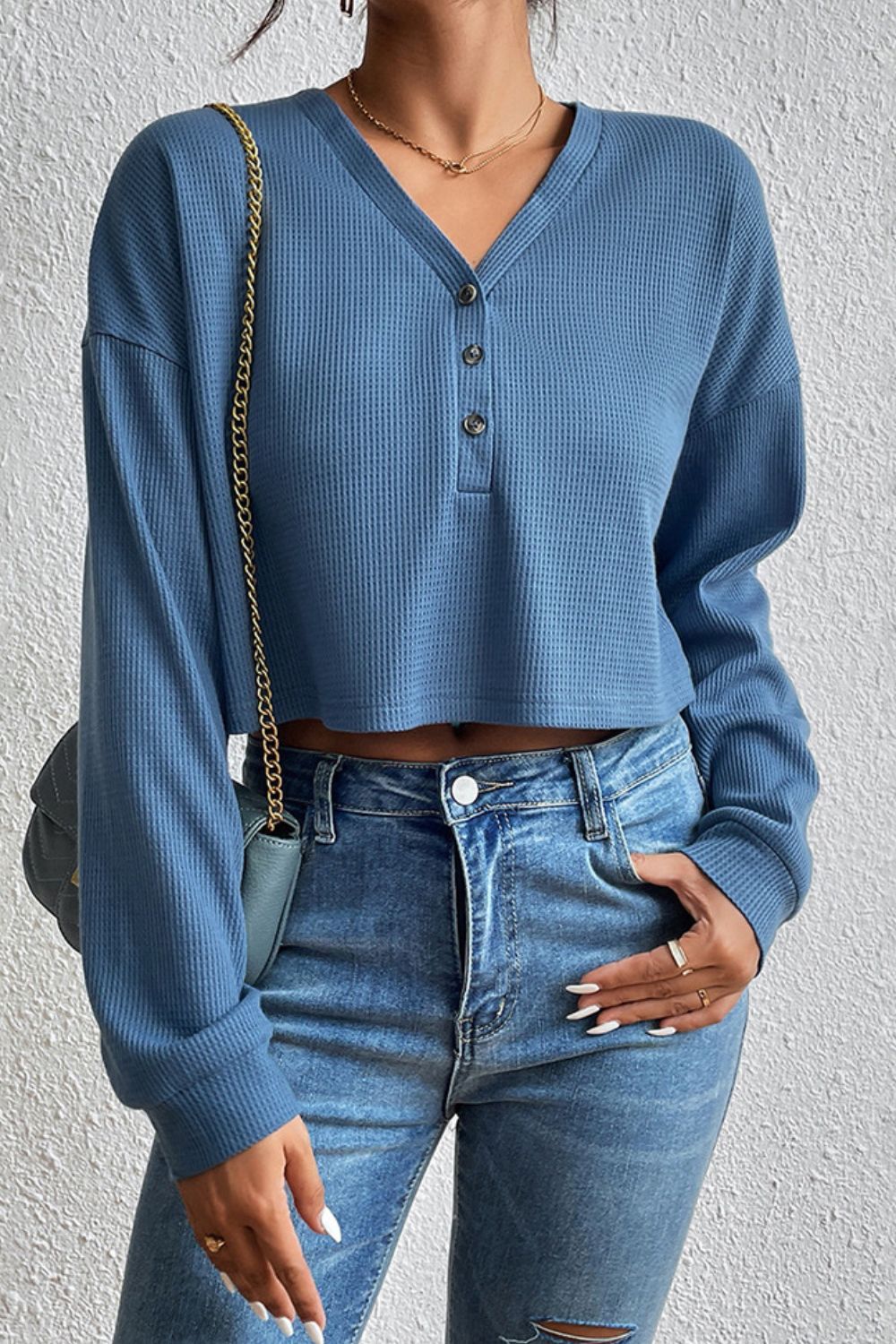 Woman wearing the dusty blue Ivy Lane cropped buttoned blouse, a key transitional layering piece for winter-to-spring in Australia