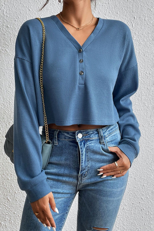 Woman wearing the dusty blue Ivy Lane cropped buttoned blouse, a key transitional layering piece for winter-to-spring in Australia